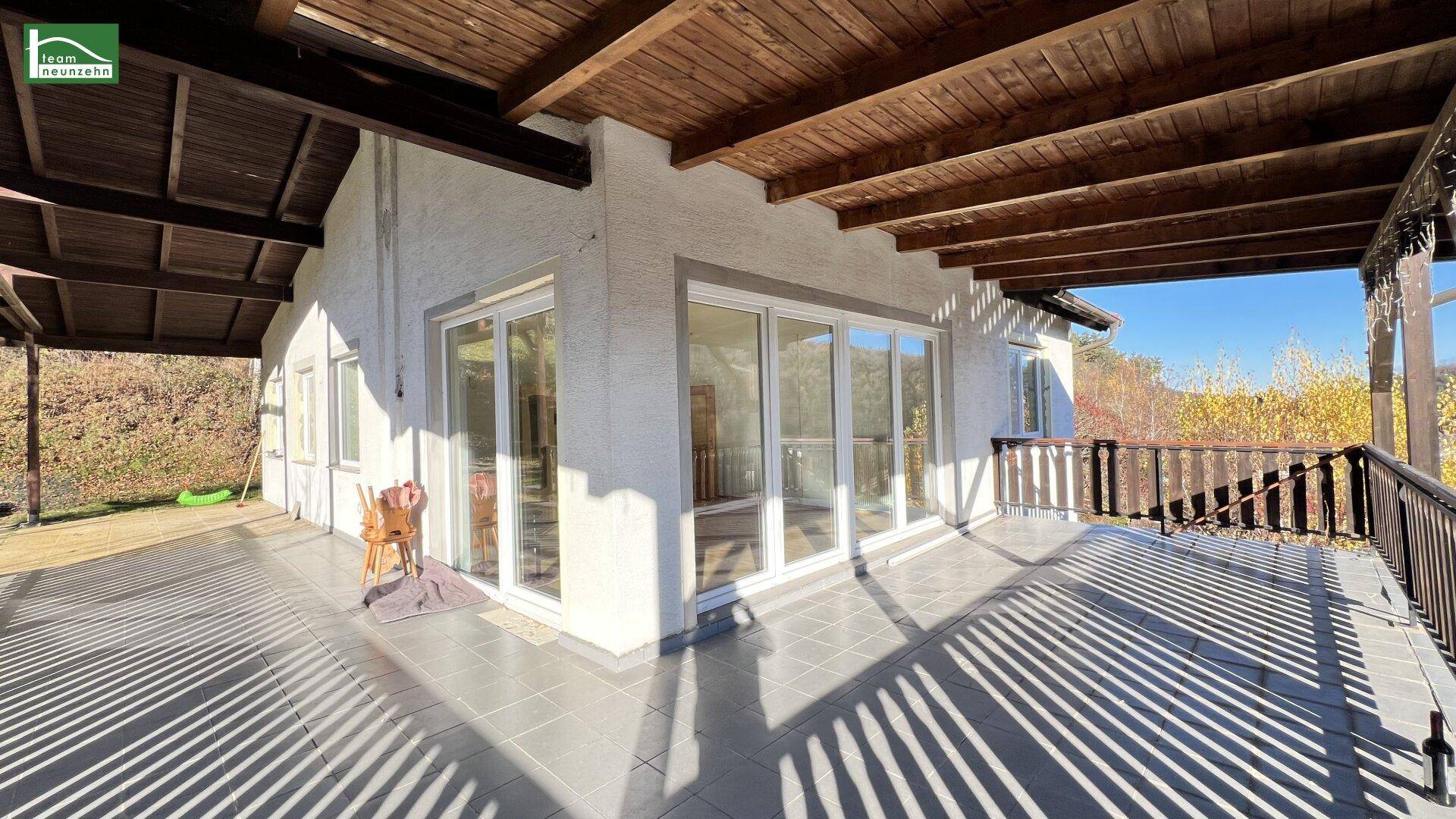 Großer überdachter Balkon mit Fliesenboden und Holzbalken, ideal für Entspannung im Freien.