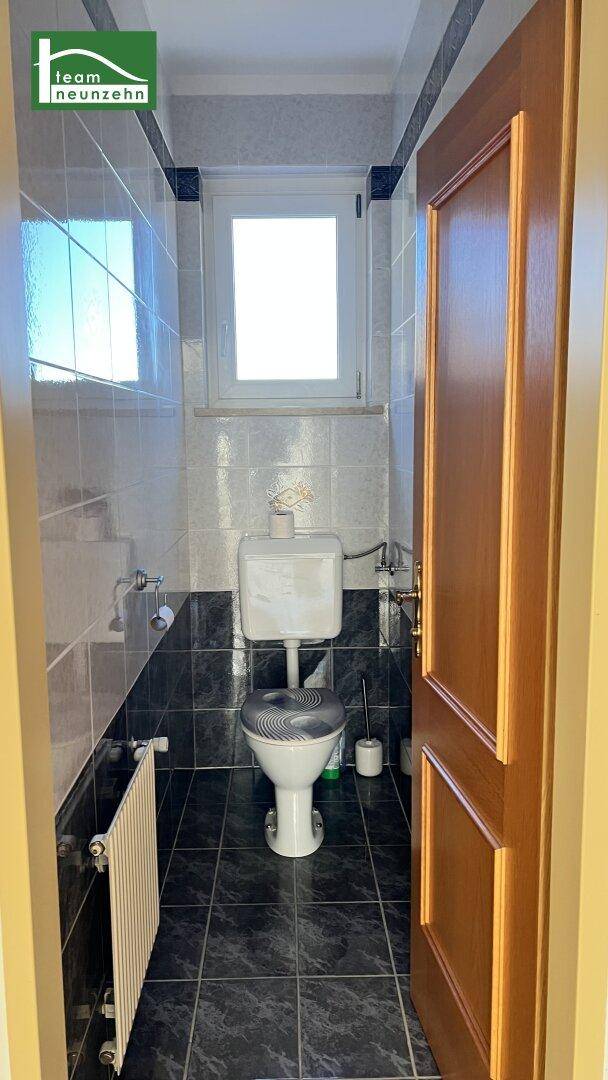 Kleines Gäste-WC mit Fenster, dunklen Fliesen und Heizkörper.