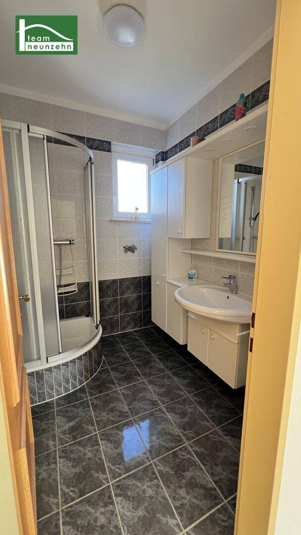 Badezimmer mit Duschkabine, Waschbecken und Spiegelschrank, in gutem Zustand.