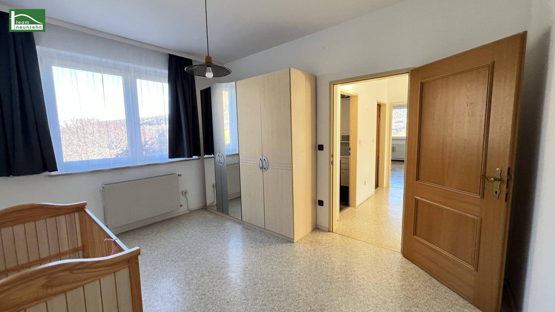 Kinderzimmer mit Terrazzoboden, großem Fenster und Kleiderschrank.