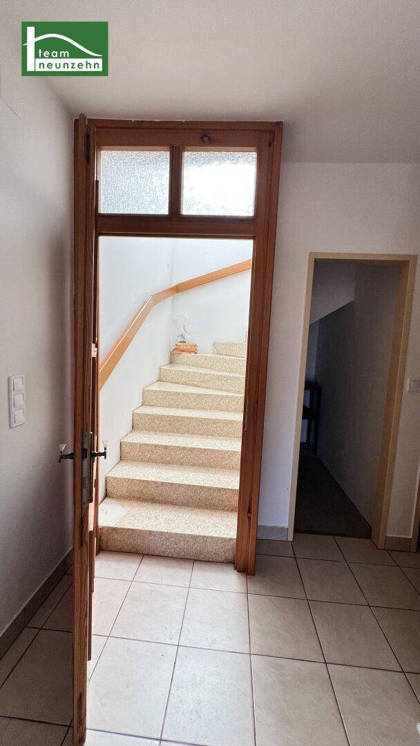 Heller Eingangsbereich mit Fliesenboden und Treppe zum Obergeschoss.