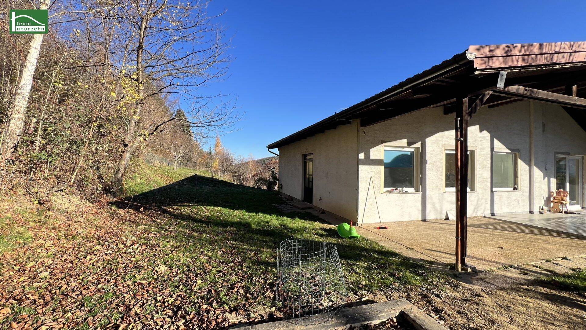Seitenansicht des Hauses mit Terrasse und angrenzendem Gartenbereich in sonniger Lage.