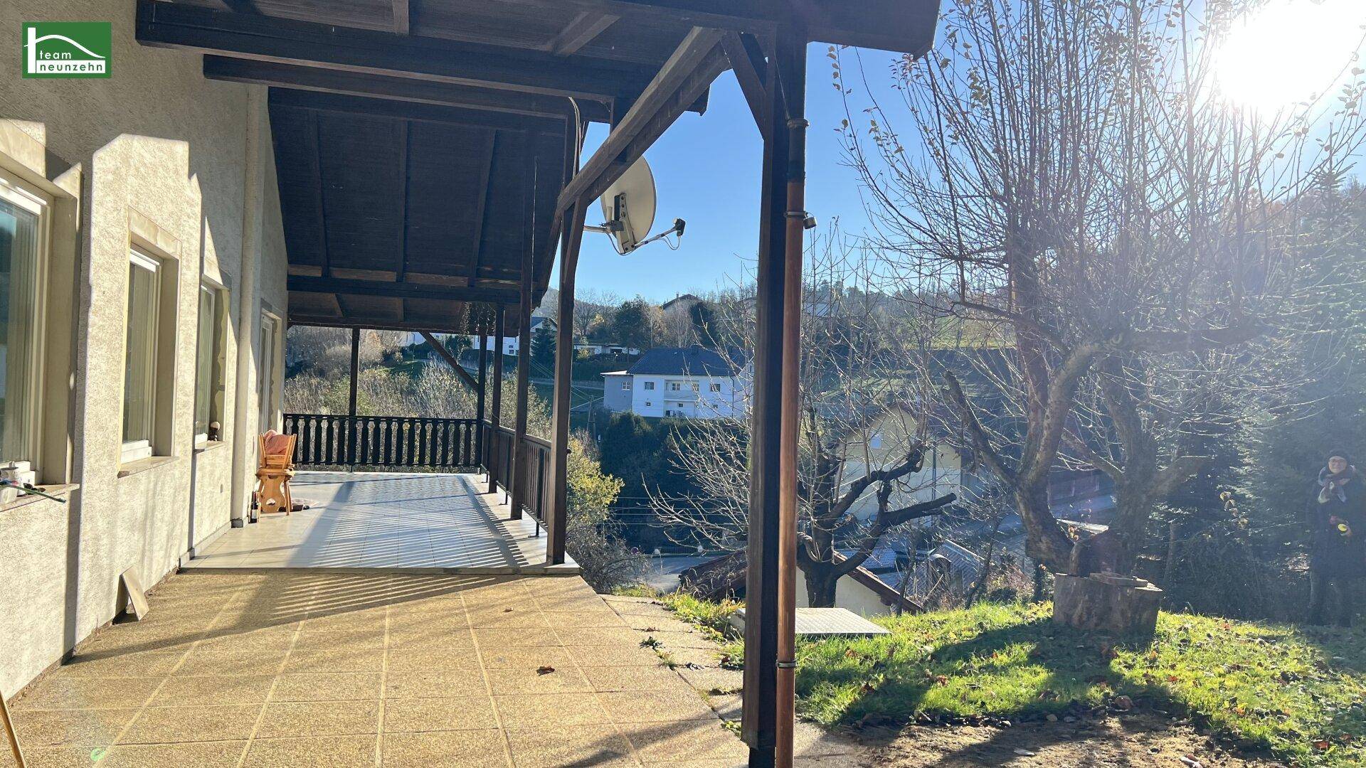 Überdachte Terrasse mit Fliesenboden und weitem Blick auf die Umgebung.