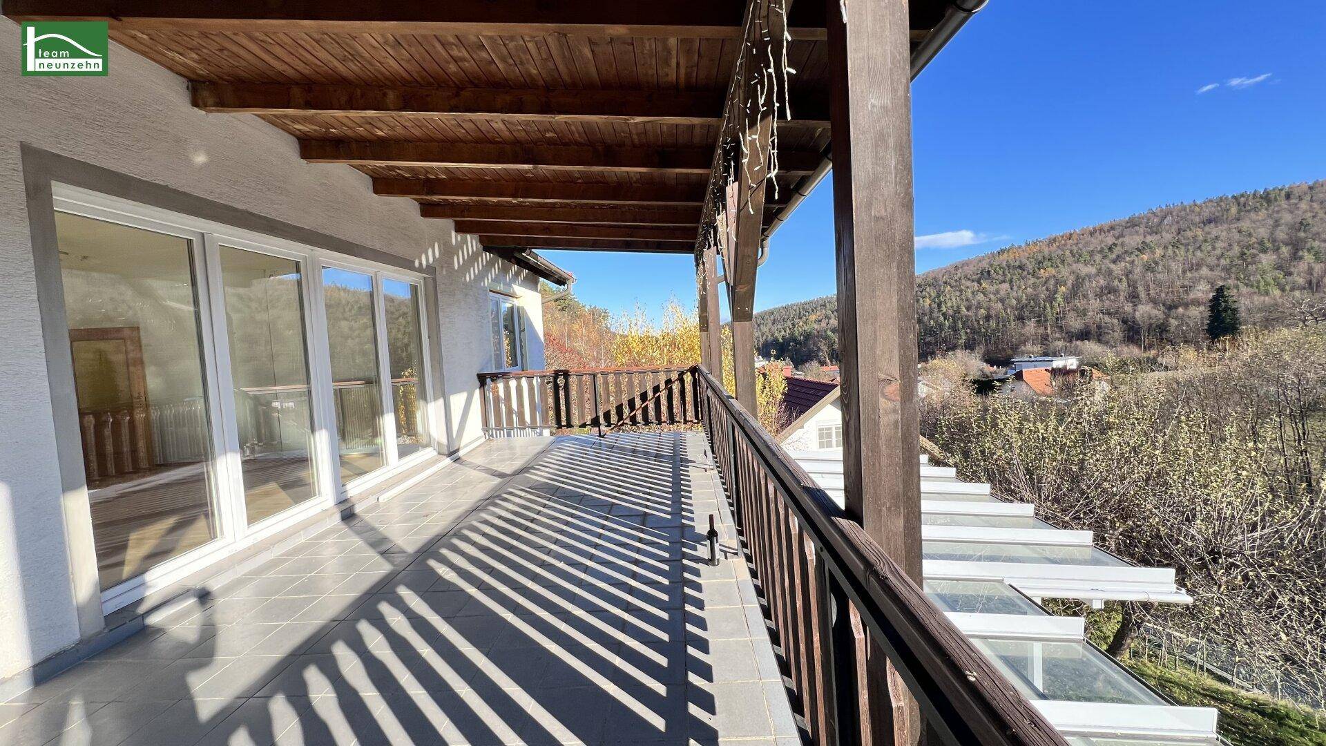 Geräumiger Balkon mit Holzbalken und weitem Blick auf die bewaldeten Hügel.