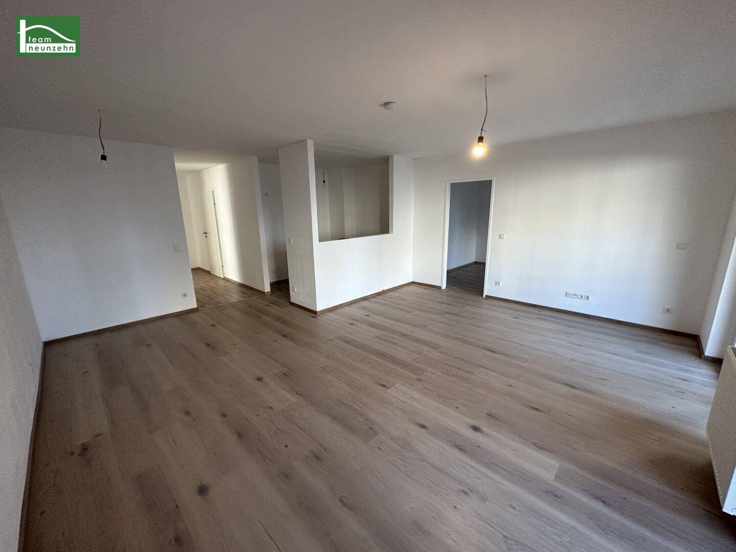Helles, leeres Wohnzimmer mit neuem Holzboden und weißen Wänden, bereit zur Gestaltung.