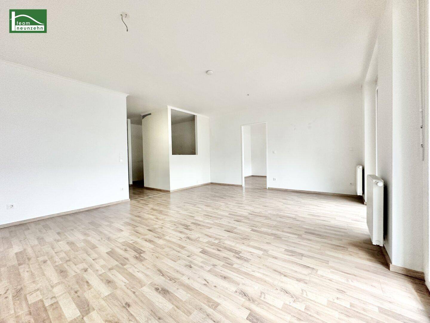 Geräumiges, helles Wohnzimmer mit Holzboden und weiß gestrichenen Wänden, ideal für individuelle Gestaltung.