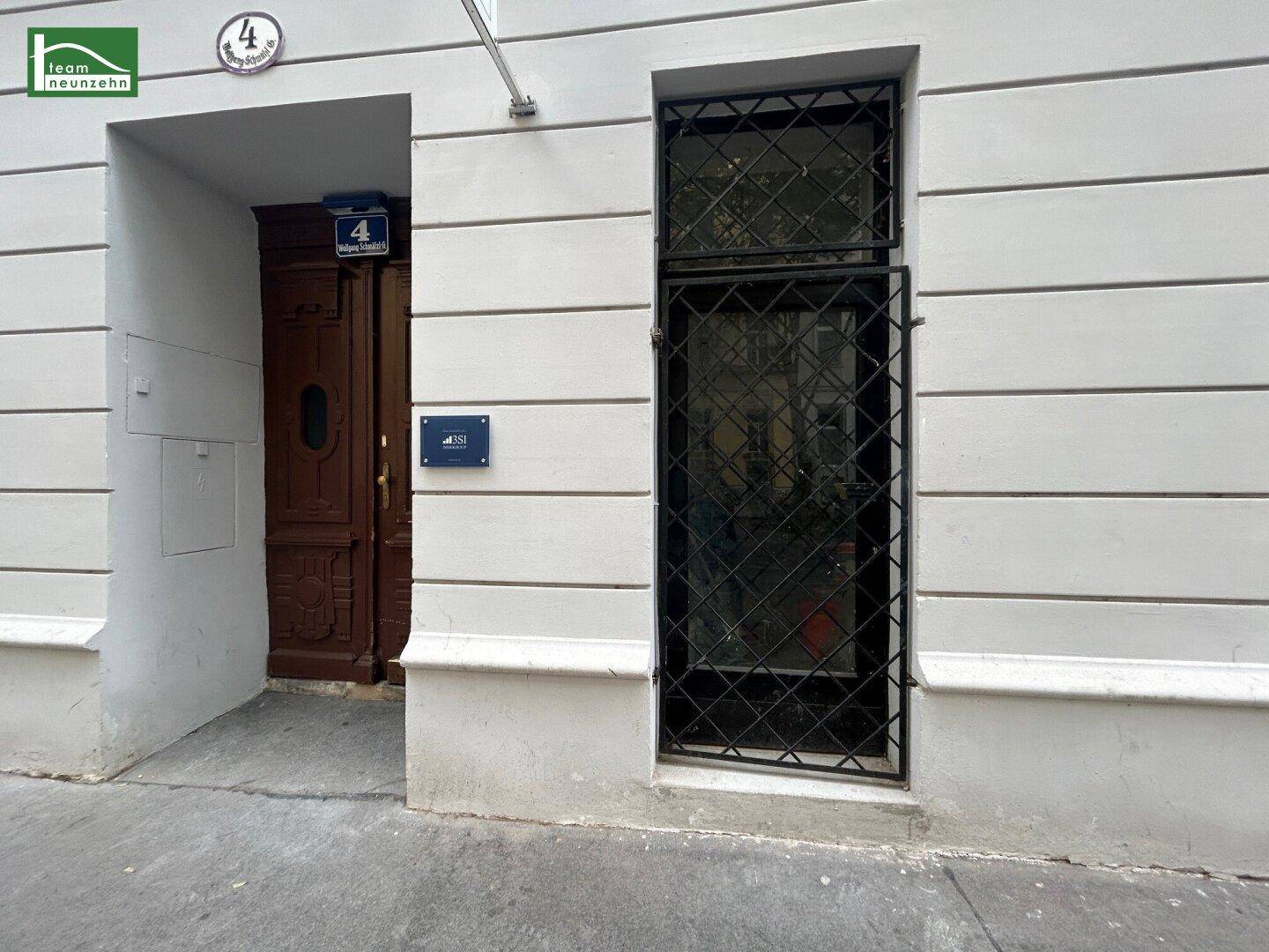 Die Fassade eines Altbaus mit einer braunen Holztür und einem Fenster mit schmiedeeisernen Sicherheitsgittern.