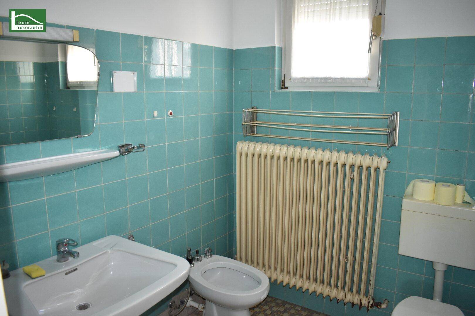 Badezimmer im Stil der 80er Jahre mit türkisfarbenen Fliesen, Waschbecken und Bidet.