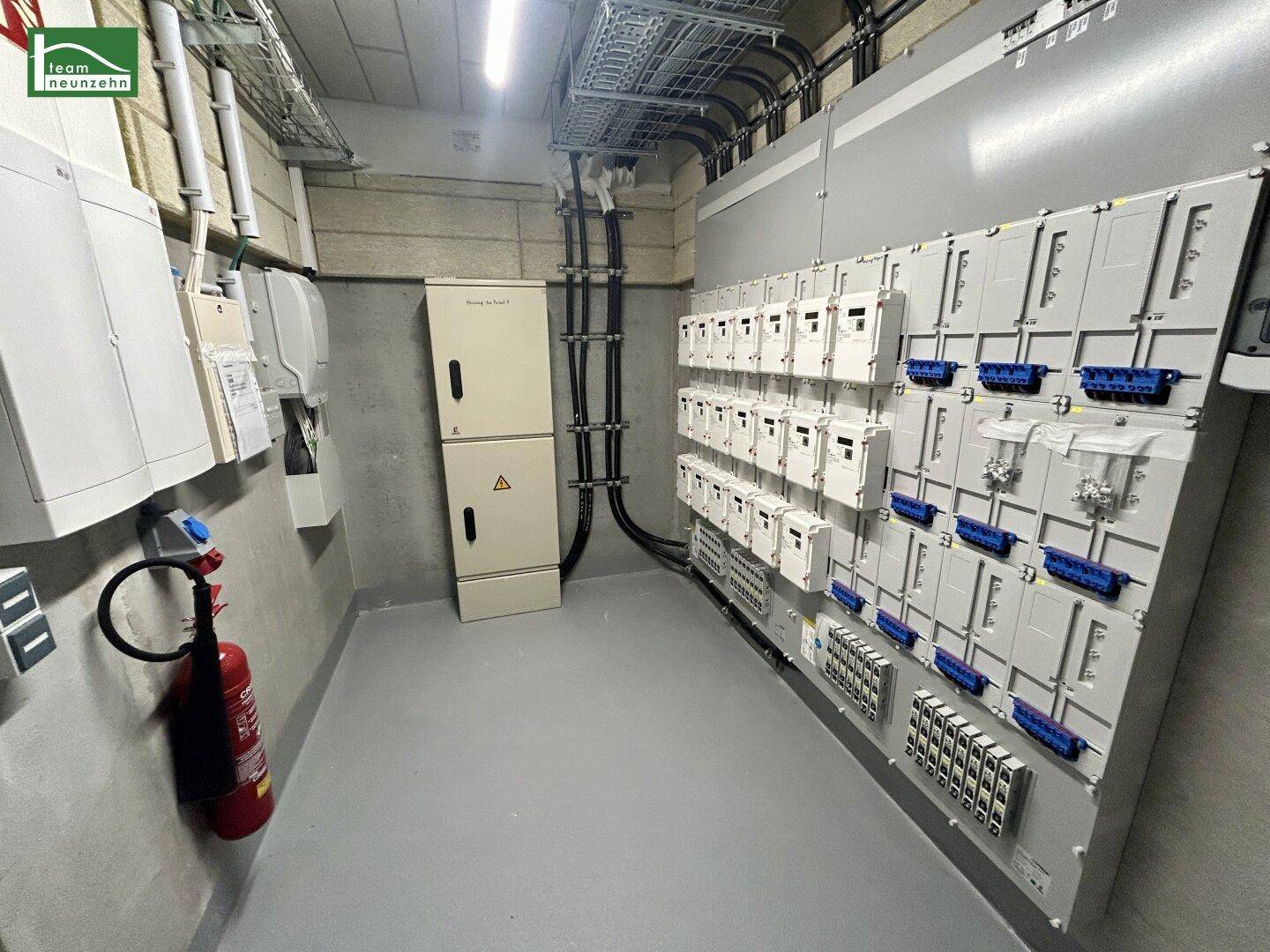 Technikraum mit zahlreichen Stromzählern, Sicherungskästen und sichtbaren Verkabelungen an der Wand.