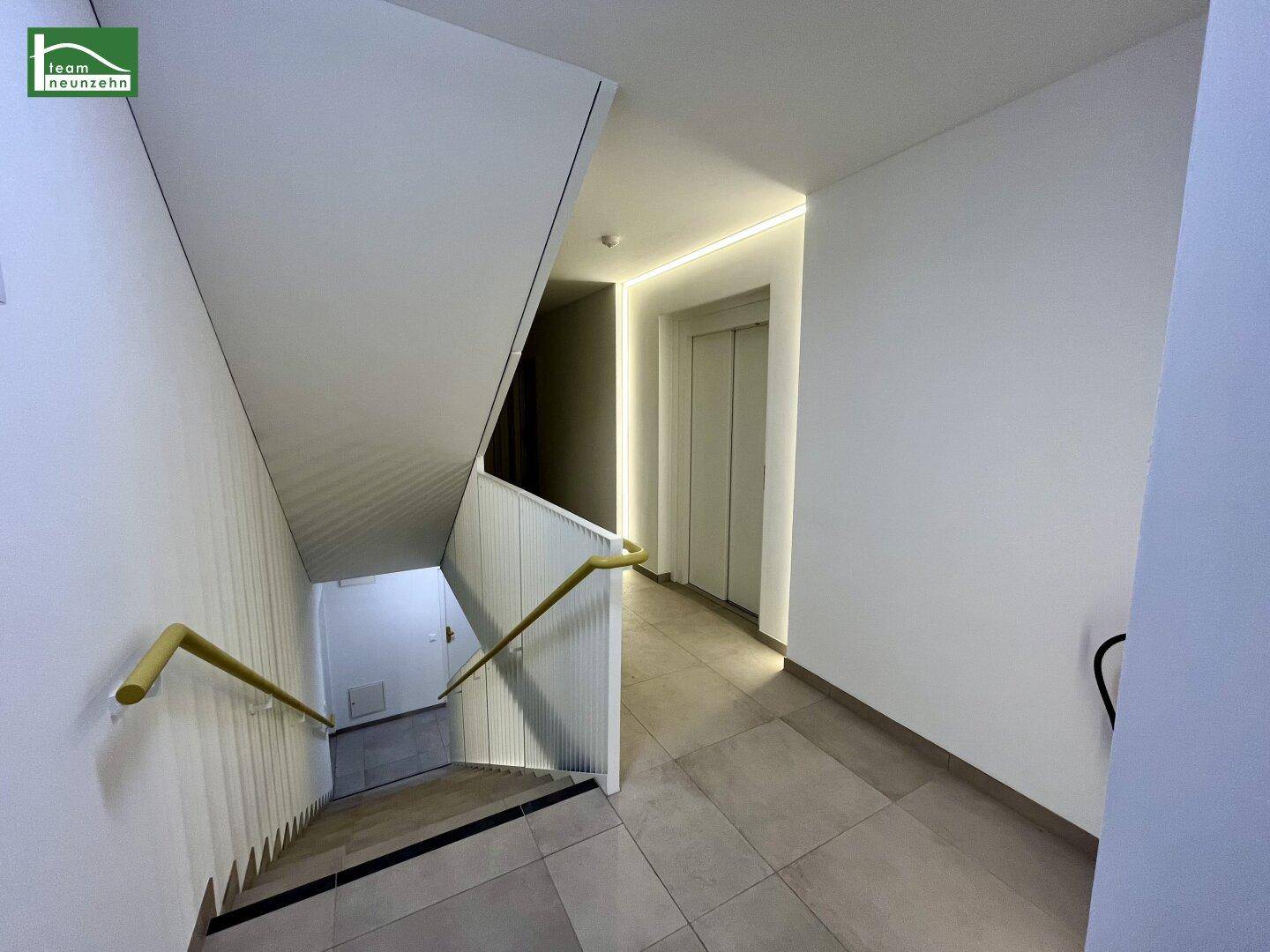 Weiterer Blick auf das Treppenhaus mit Aufzug und moderner, indirekter Beleuchtung.