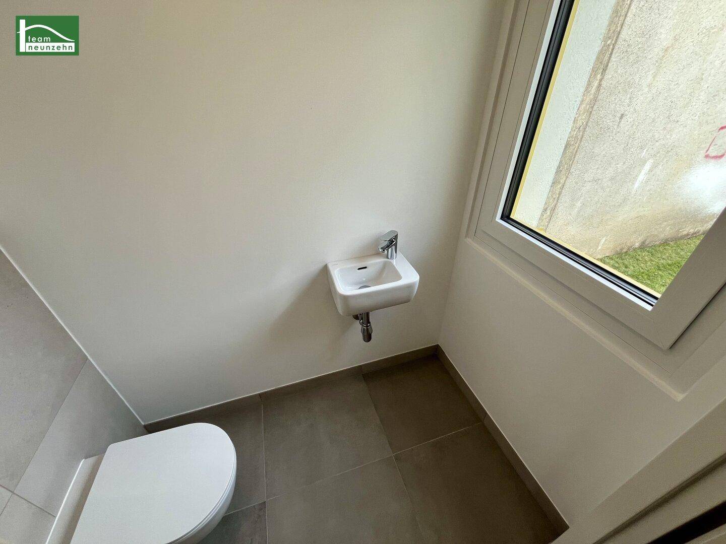 Kleines Gäste-WC mit Waschbecken und Fenster.