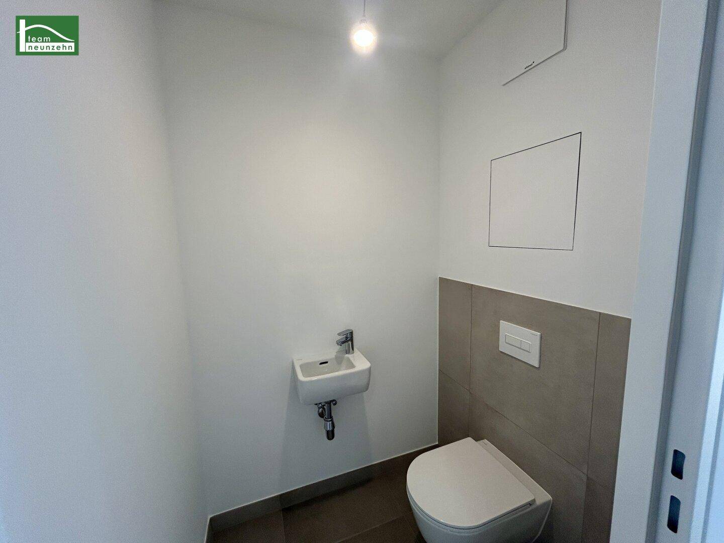 Kleines, modernes Gäste-WC mit Wand-WC und Handwaschbecken, in neutralen Farben gehalten.