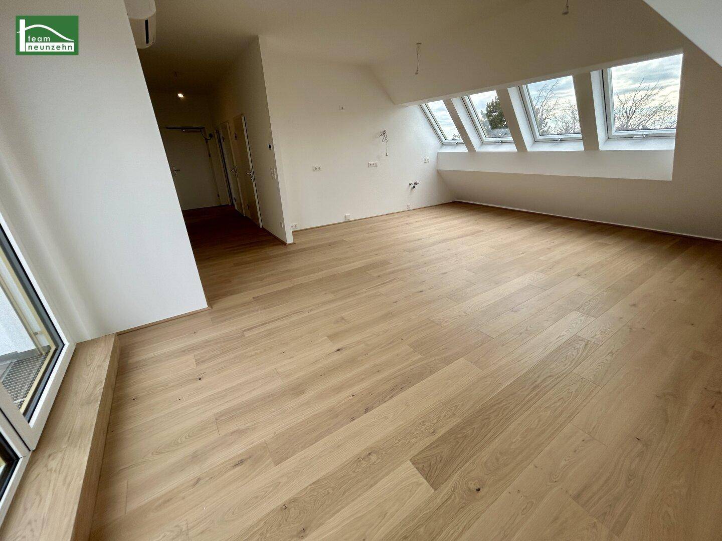 Helles, geräumiges Zimmer im Dachgeschoss mit Holzboden und großen Dachfenstern, ideal als Wohn- oder Schlafbereich.