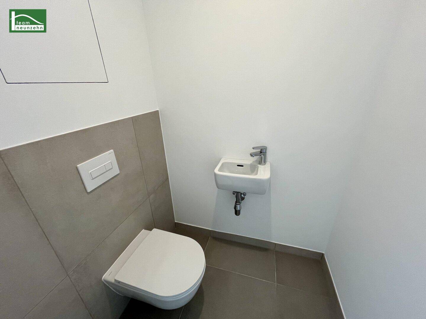 Kleines Gäste-WC mit wandhängender Toilette und kompaktem Waschbecken, modern gefliest.