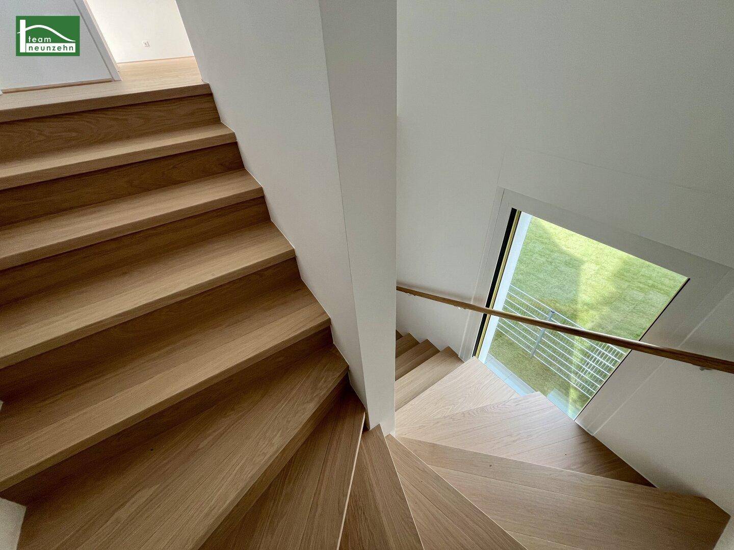 Elegante Holztreppe mit natürlichem Lichteinfall durch ein großes Fenster.