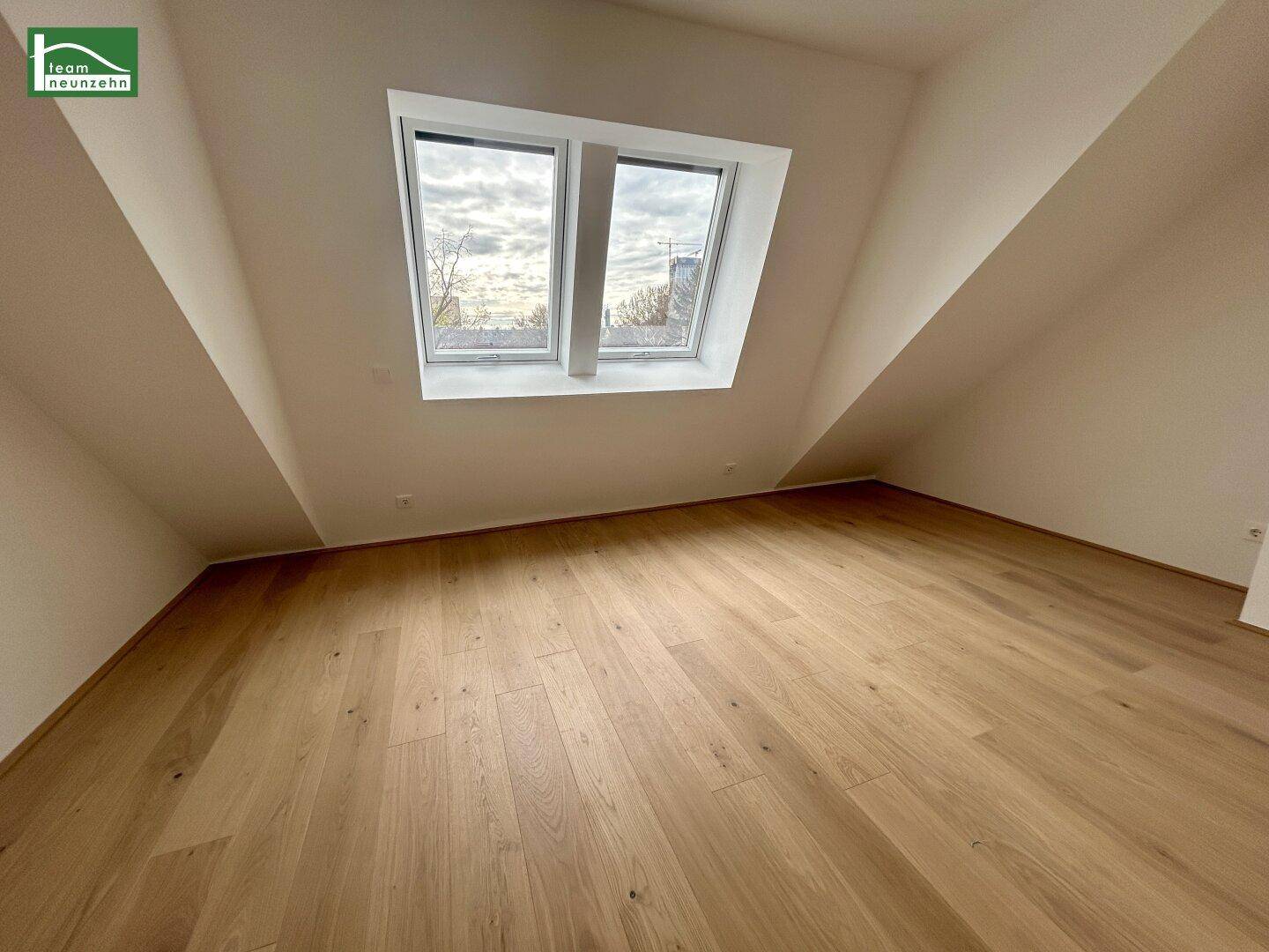 Ruhiger Dachgeschossraum mit Holzboden und zwei Dachfenstern, ideal als Schlaf- oder Arbeitszimmer.
