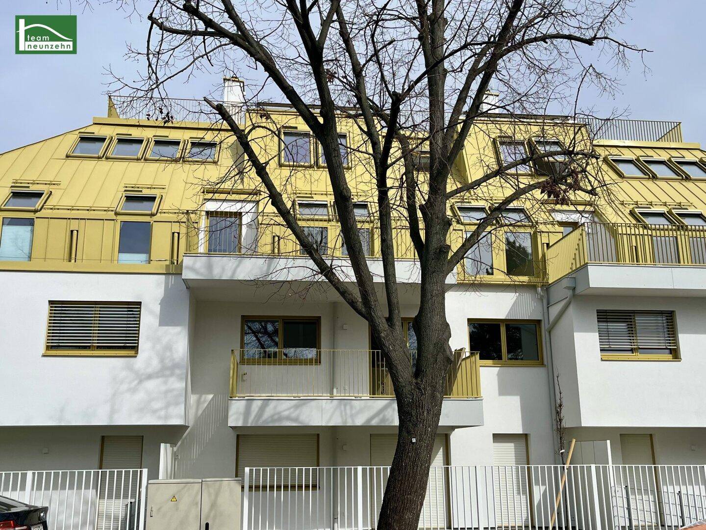 Ansicht des modernen Wohngebäudes mit markantem goldenem Dach und Balkonen.