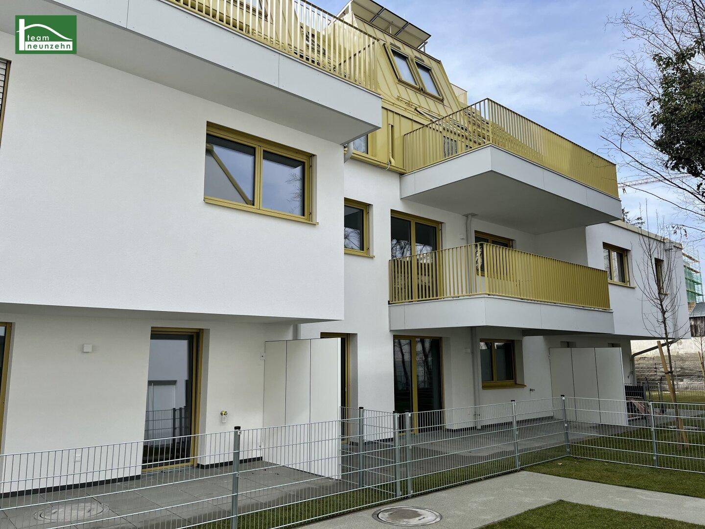 Moderne Wohnanlage mit Erdgeschosswohnungen, kleinen Gärten und Balkonen.