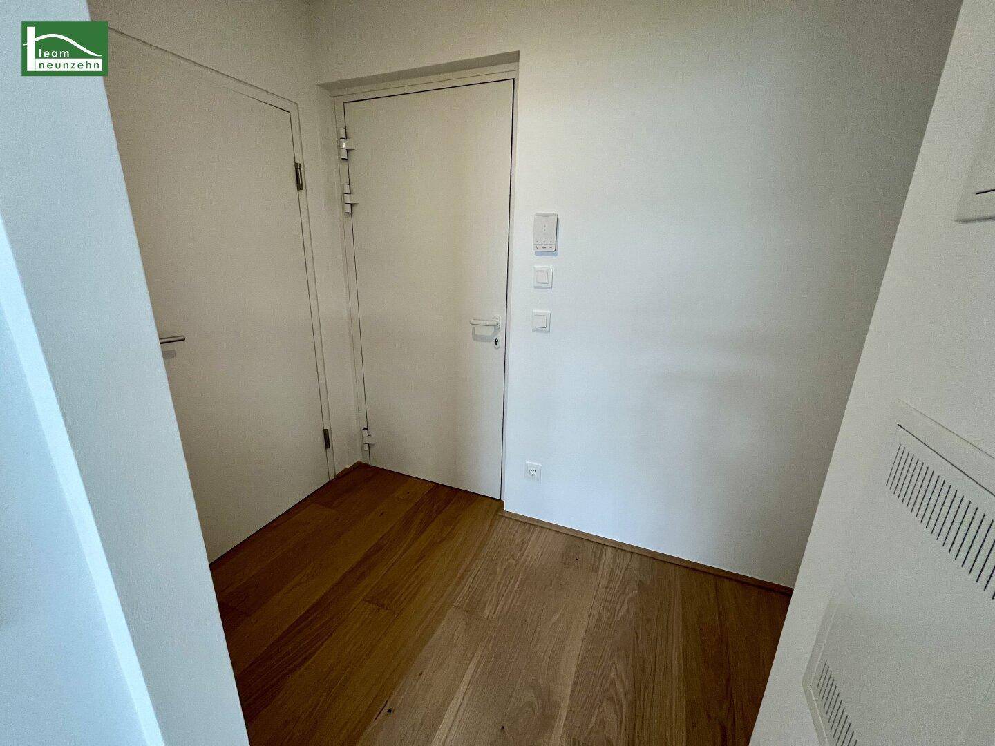 Kleiner Flurbereich mit Holzboden und zwei weißen Türen, schlicht und funktional.