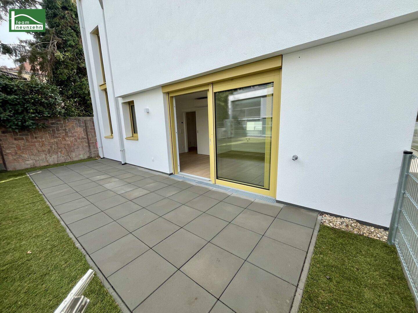 Große gepflasterte Terrasse mit Rasenfläche und Zugang zum Innenbereich des Hauses.
