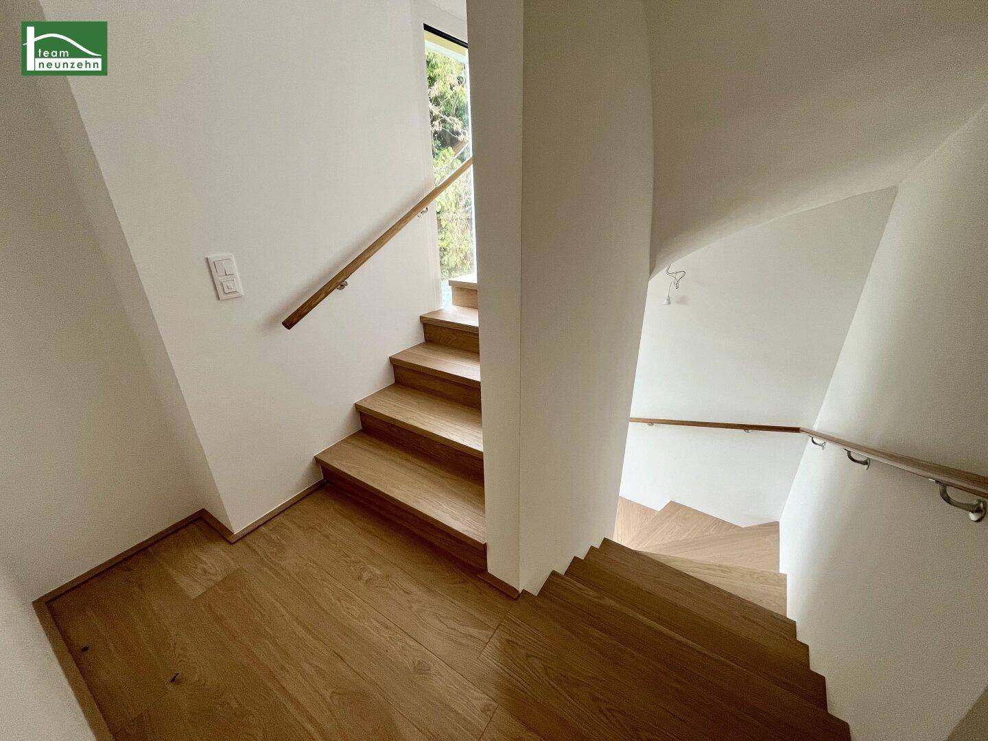 Elegante Holztreppe mit Handläufen, die die verschiedenen Ebenen des Hauses verbindet.