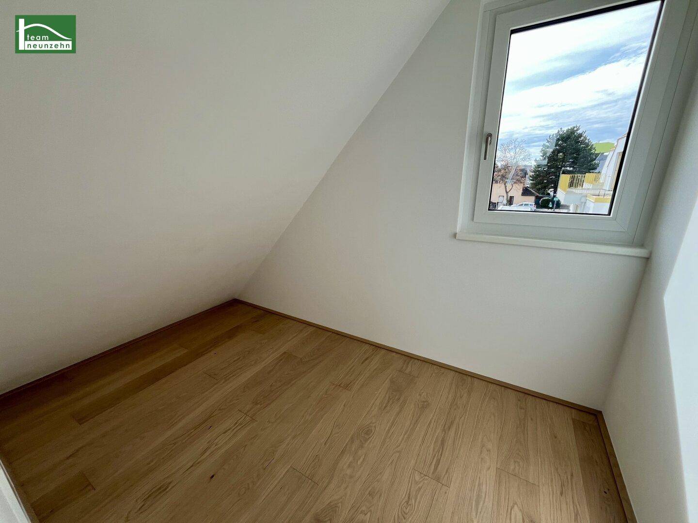 Gemütliches Zimmer im Dachgeschoss mit Holzboden und Fenster, ideal als Kinderzimmer.