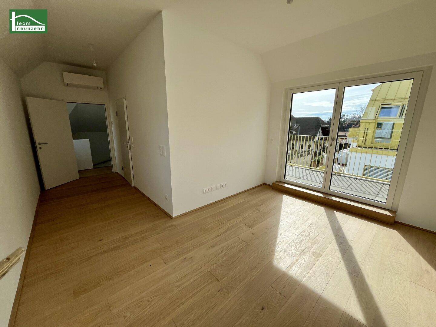 Helles Schlafzimmer mit Holzboden und Fenster mit Blick auf die Umgebung.