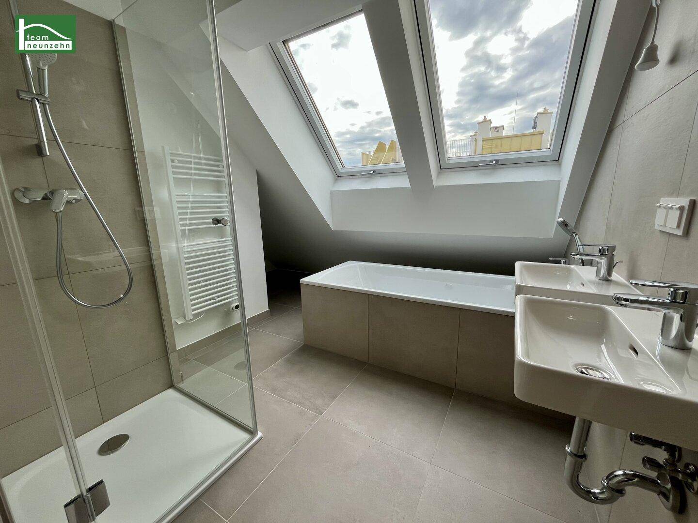 Modernes Badezimmer mit Doppelwaschbecken, Badewanne, Dusche und Dachfenstern für natürliches Licht.