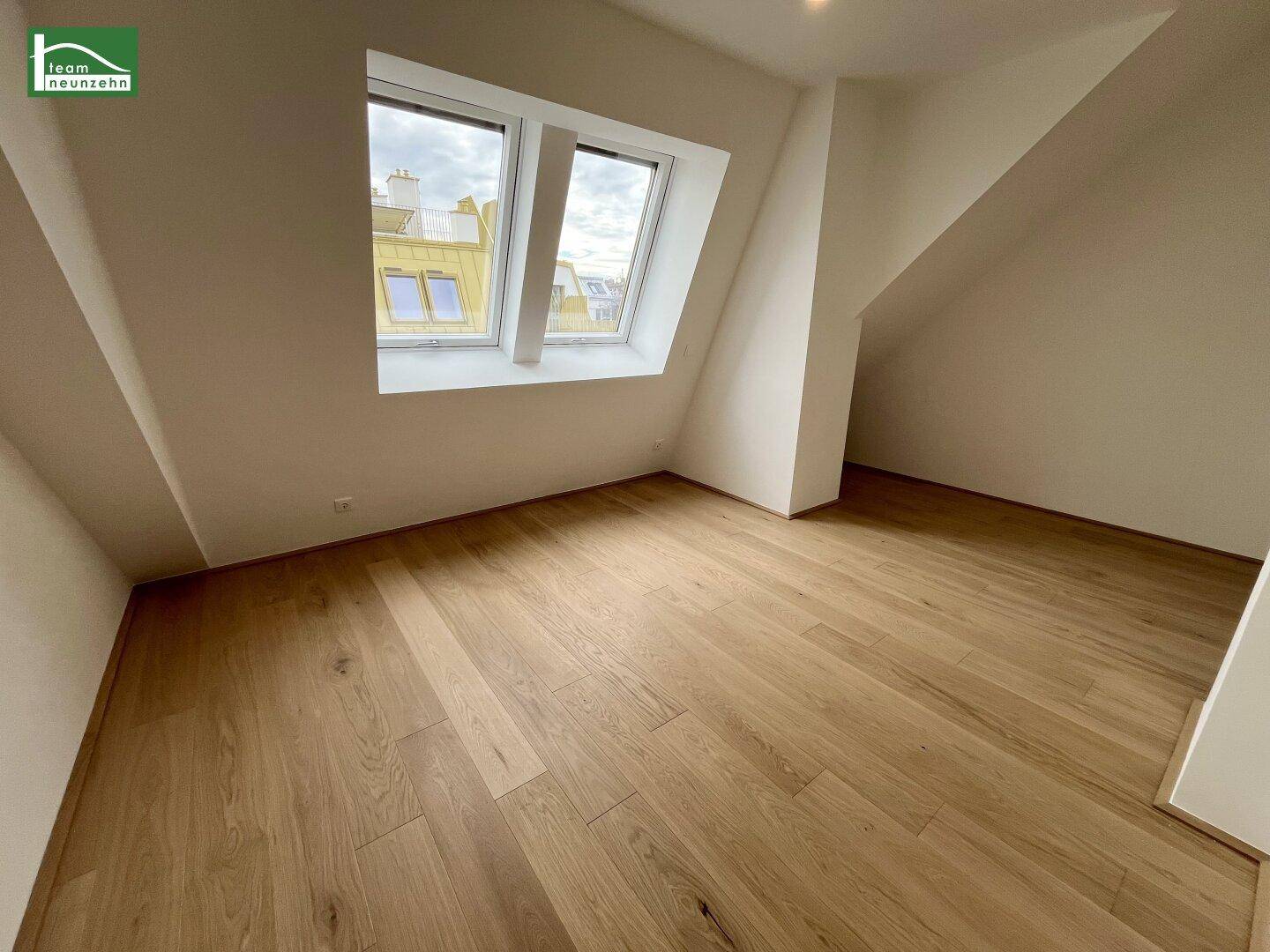 Helles Schlafzimmer mit Holzboden und Dachfenstern, die viel Tageslicht hereinlassen.