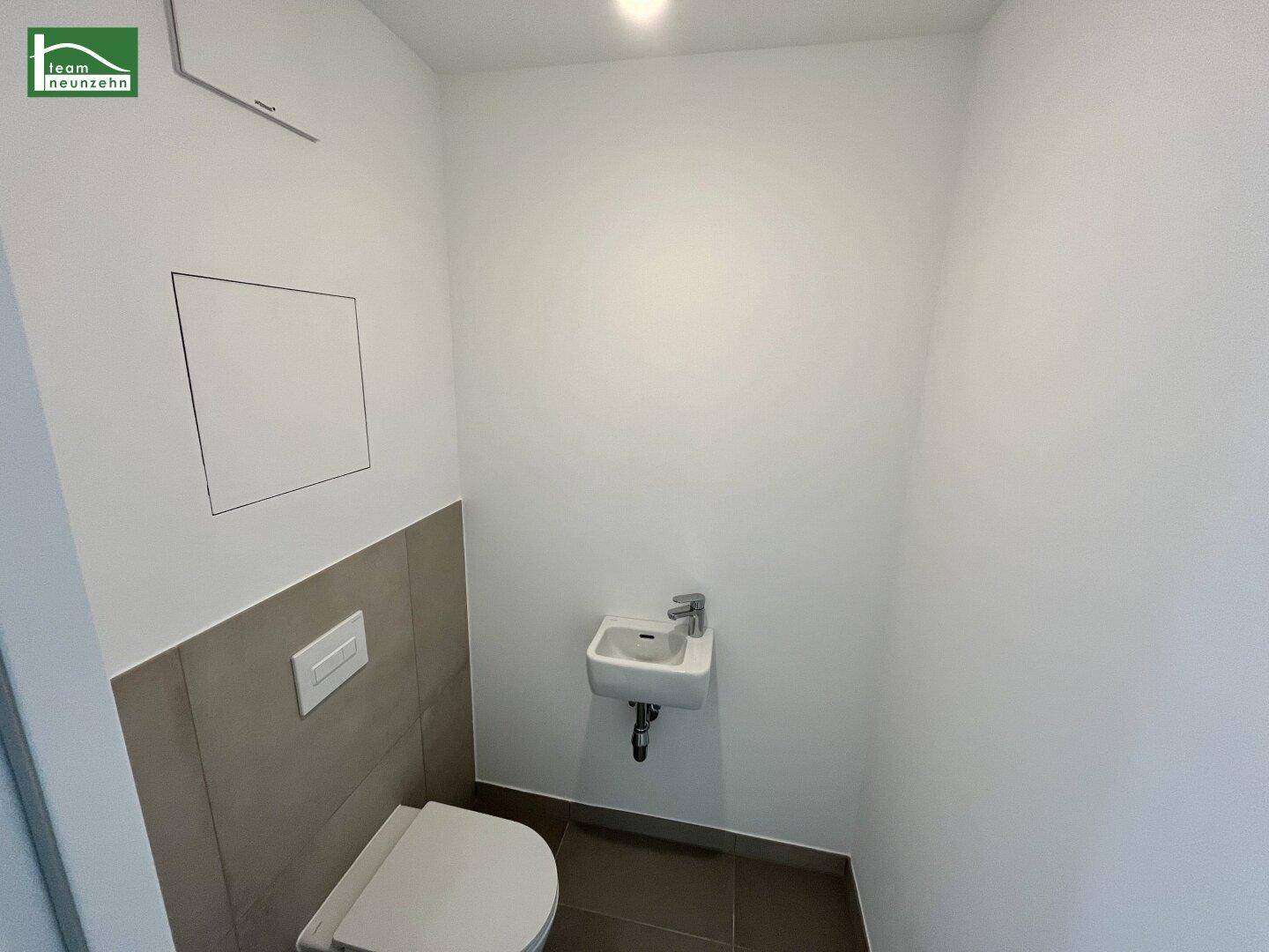 Modernes Gäste-WC mit wandmontierter Toilette und kleinem Waschbecken, sauber und funktional.