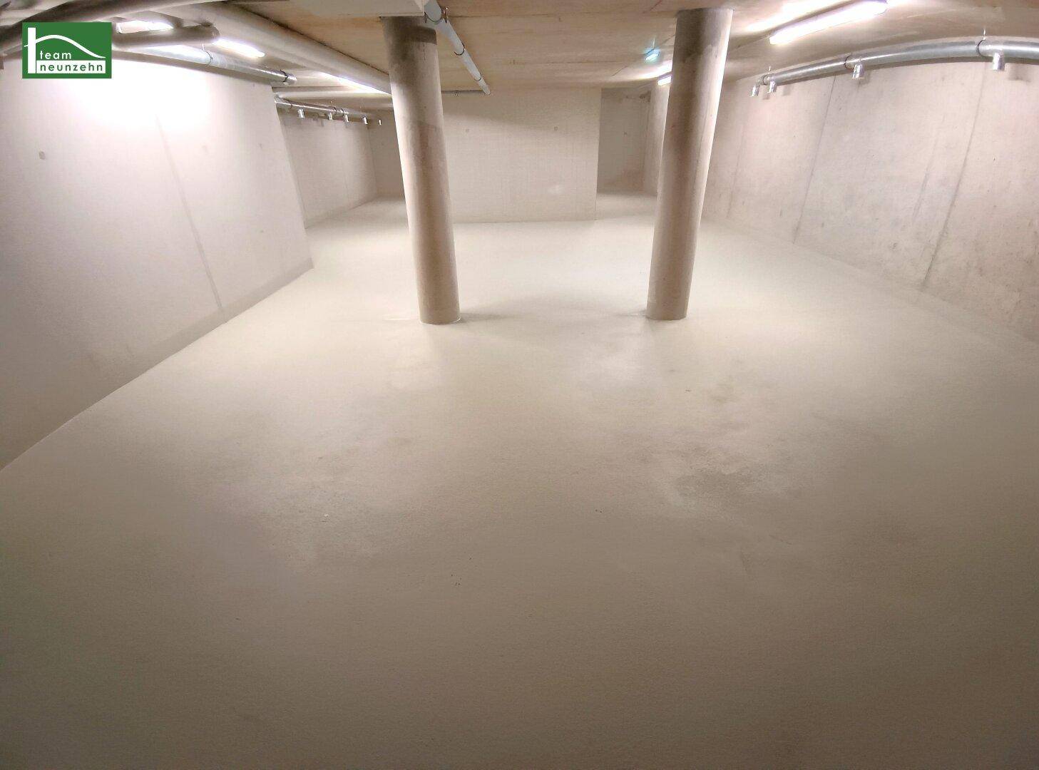 Großer, unfertiger Kellerraum mit Betonsäulen und sichtbaren Leitungen an der Decke.