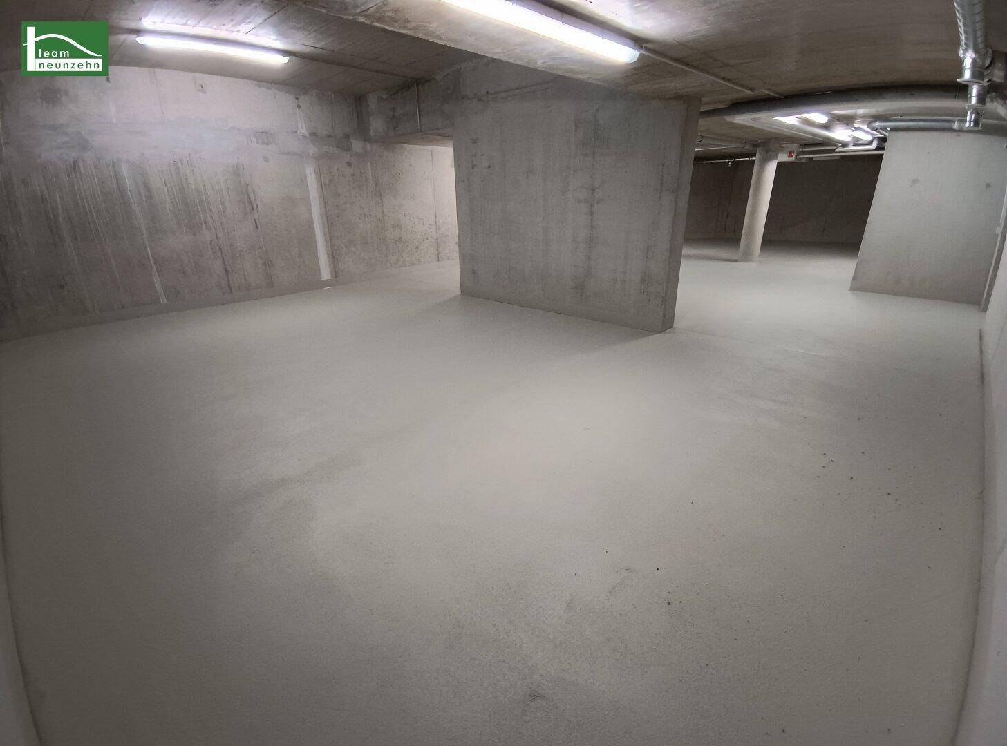 Unfertiger Kellerraum mit Betonwänden, Säulen und sichtbaren Installationen an der Decke.