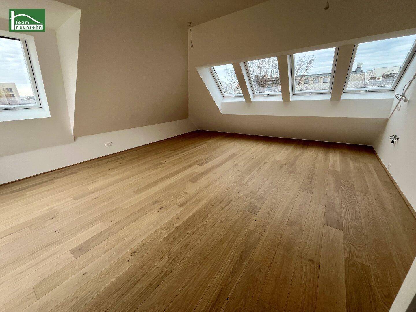 Heller Raum mit Holzboden und mehreren Dachfenstern, bietet viel natürliches Licht.