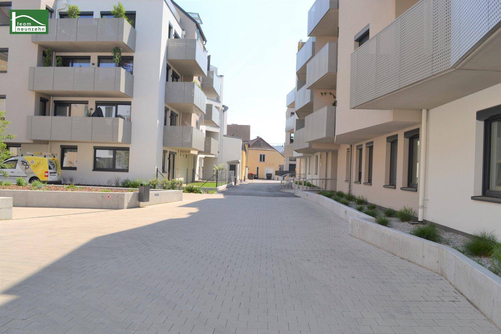 Moderne Wohngebäude mit Balkonen und gepflastertem Zugangsweg in einer städtischen Umgebung.
