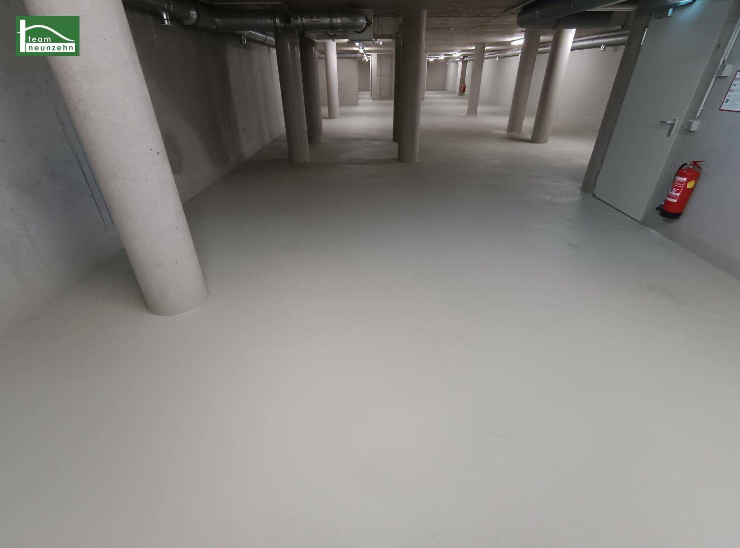 Leerer, weitläufiger Kellerraum mit Betonpfeilern und glattem Boden, ideal als Lagerfläche.
