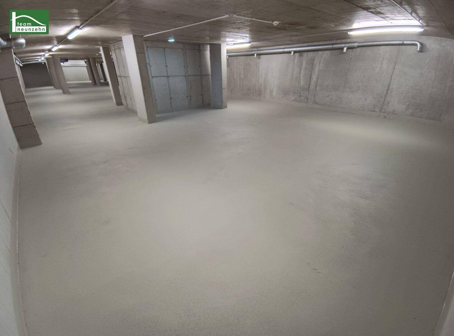 Geräumiger Kellerbereich mit Betonwänden und -säulen, beleuchtet von Deckenleuchten.