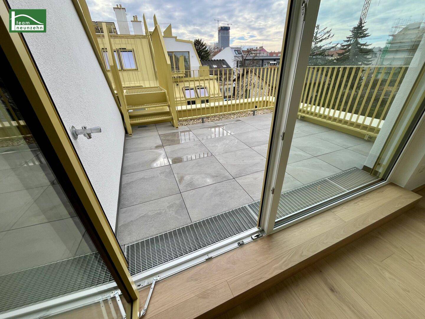 Zugang zu einer gefliesten Terrasse mit gelbem Geländer und Blick auf die Umgebung.