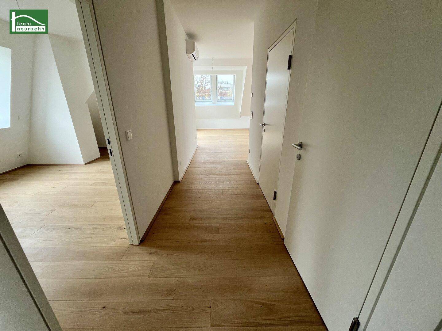 Heller Flur mit Holzboden, der zu verschiedenen Räumen und einem weiteren Bereich führt.