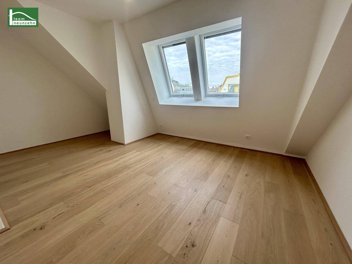 Helles Zimmer mit Holzboden und Dachfenstern, ideal für ein Schlafzimmer oder Büro.