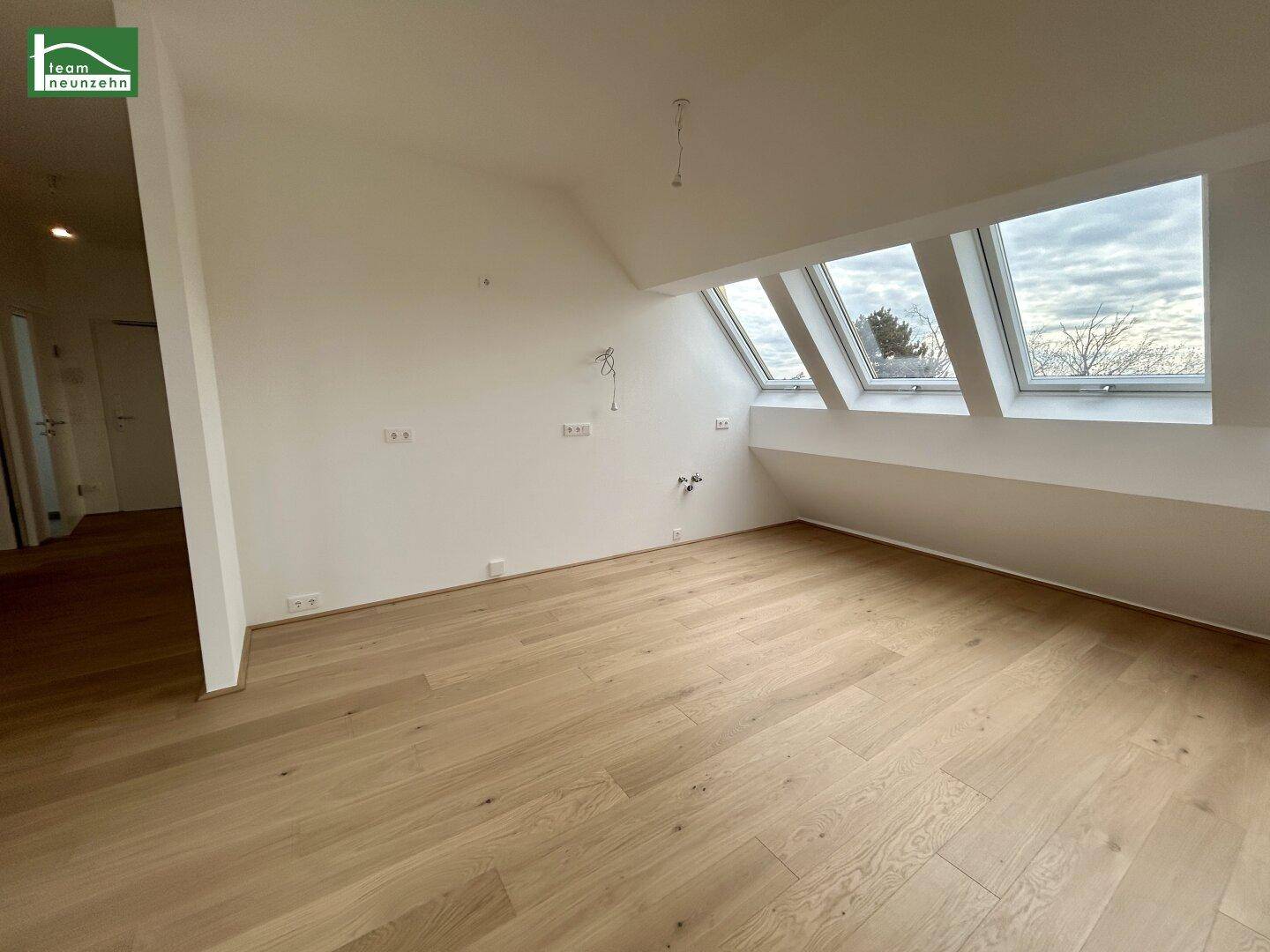 Geräumiger Wohnbereich mit Holzboden und einer Reihe von Dachfenstern.