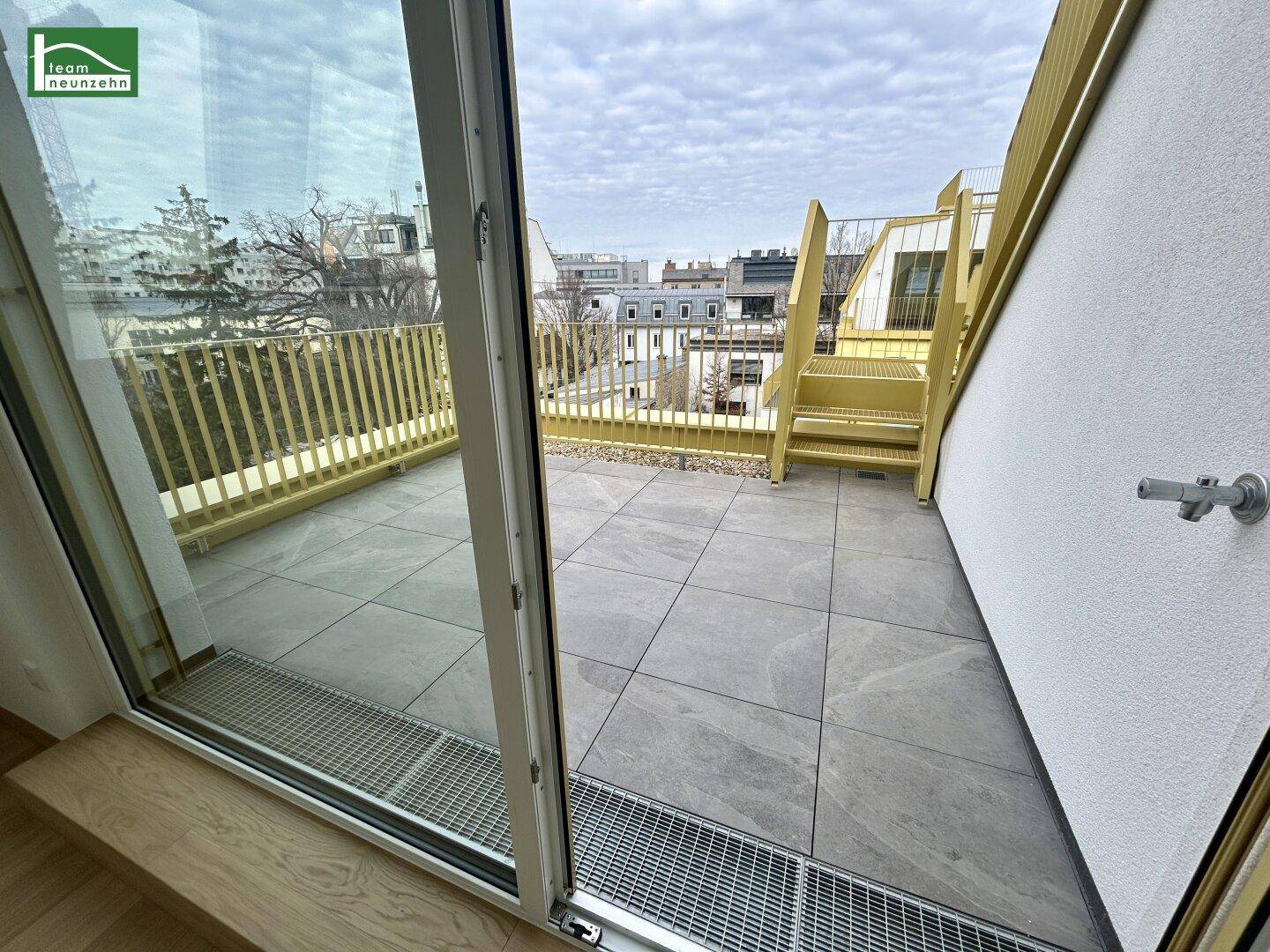 Geräumige Dachterrasse mit Fliesenboden und Blick auf die Umgebung.
