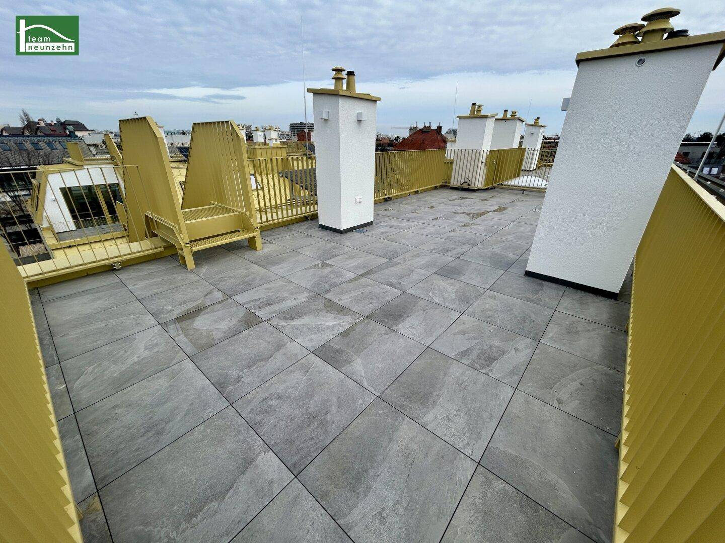 Obere Dachterrasse mit gelbem Geländer und weitem Blick über die Dächer.