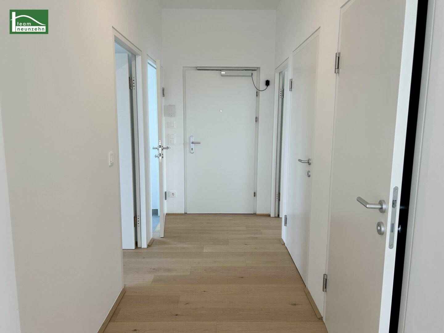 Heller Flur mit Holzboden und mehreren Türen, führt zu verschiedenen Räumen.