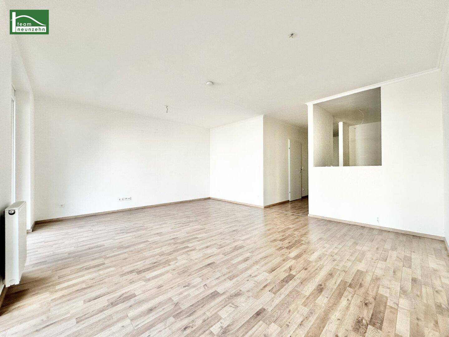 Helles, leeres Zimmer mit Laminatboden und weißen Wänden, bereit zur individuellen Gestaltung.