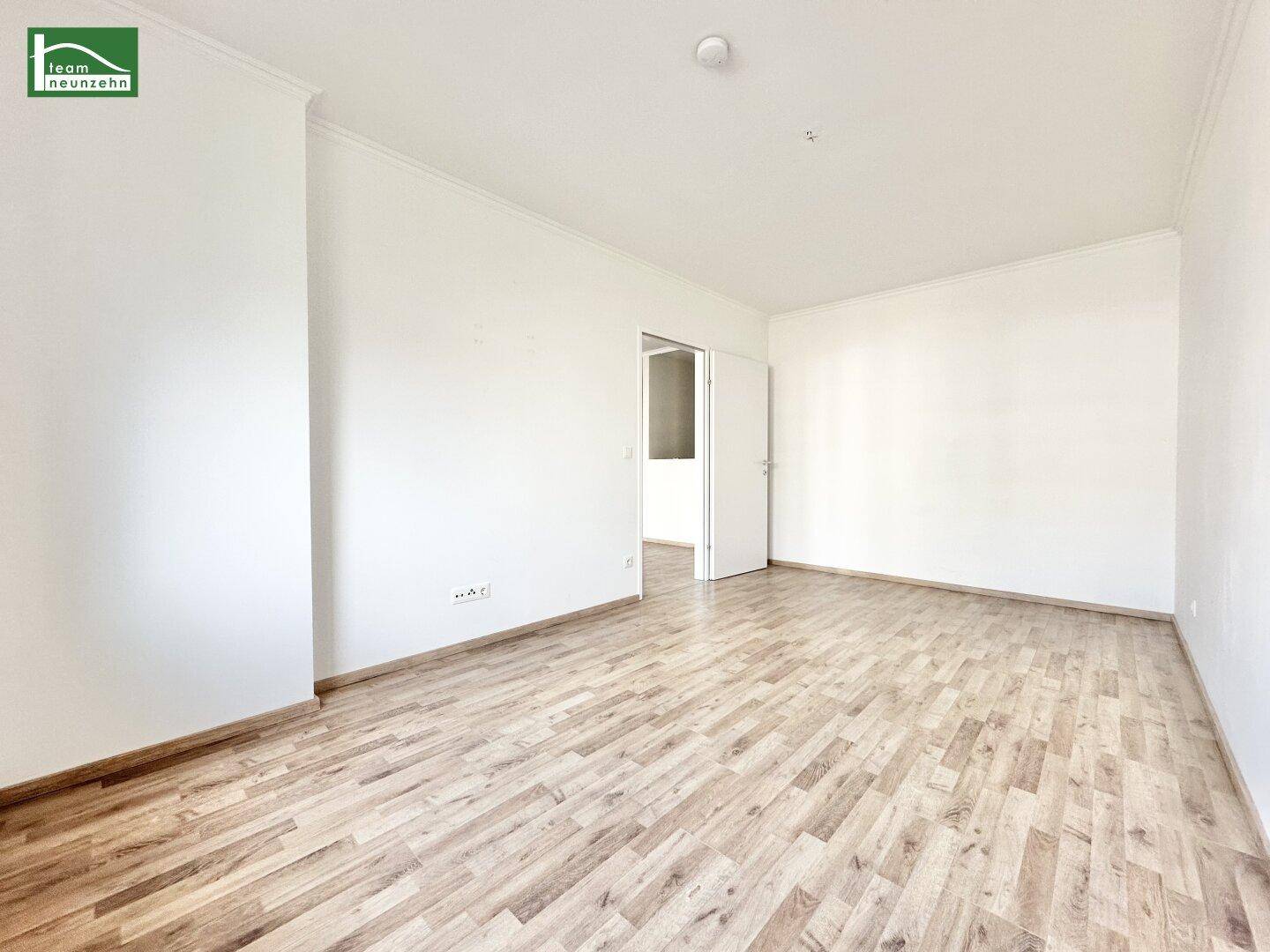 Unmöbliertes Zimmer mit Laminatboden und weiß gestrichenen Wänden, bereit zum Einzug.