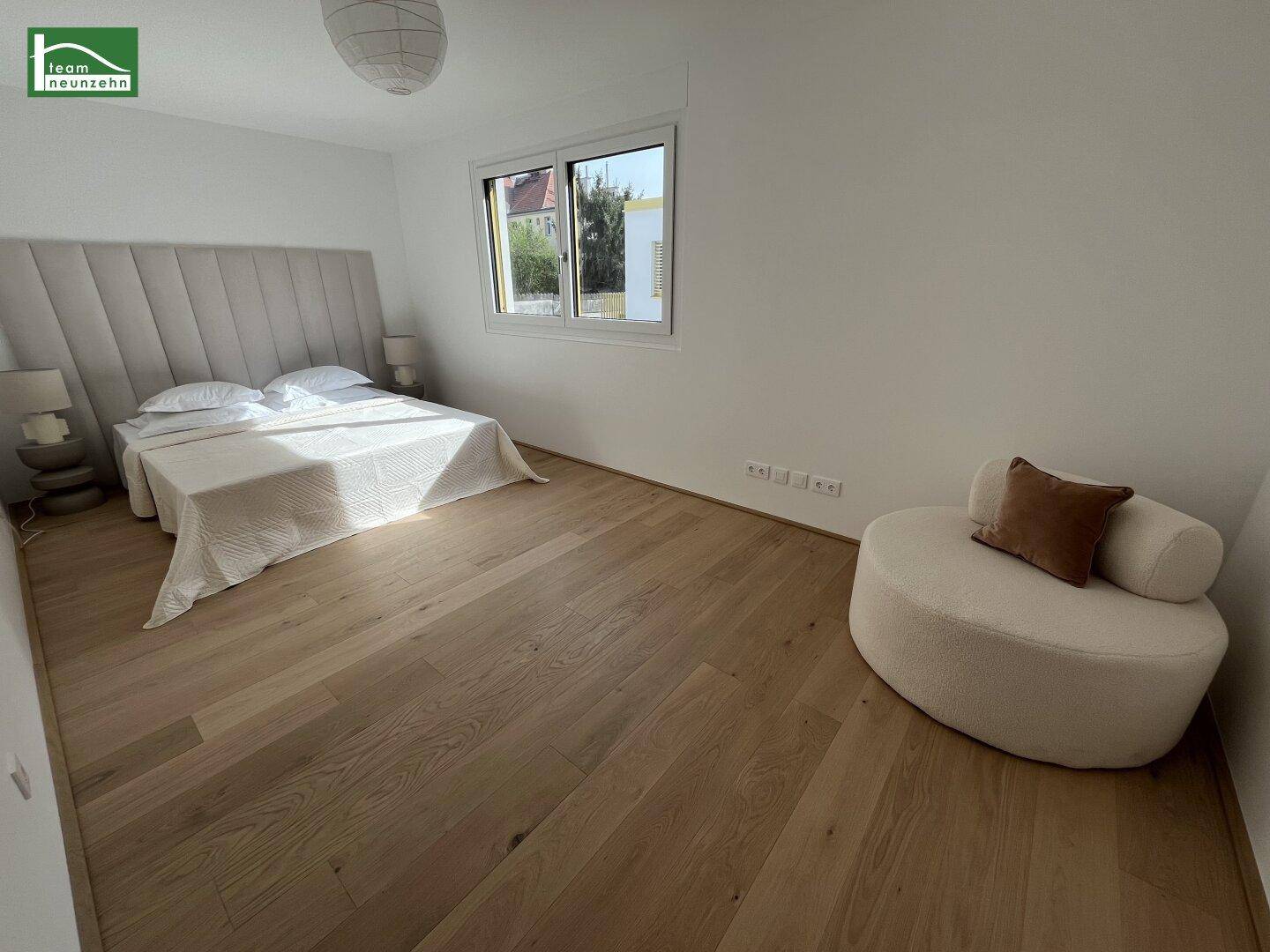 Geräumiges Schlafzimmer mit hellem Holzboden, großem Bett und viel natürlichem Lichteinfall.