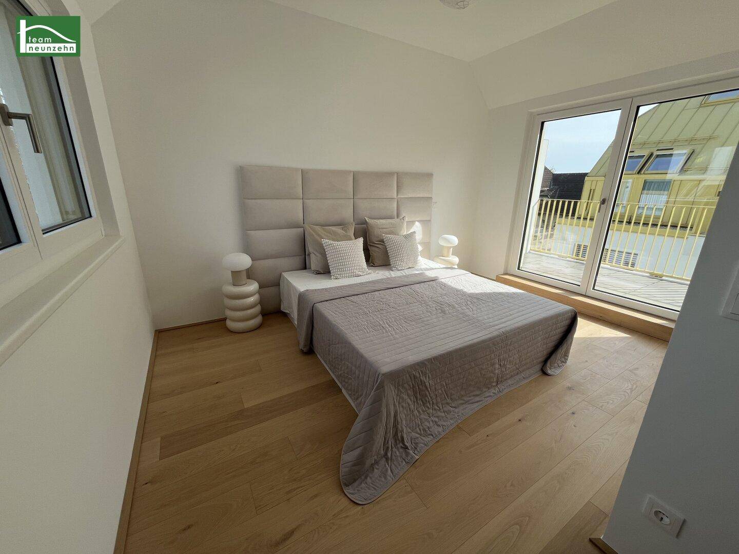 Helles Schlafzimmer mit Holzboden, modernem Bett und direktem Zugang zu einem Balkon oder einer Terrasse.