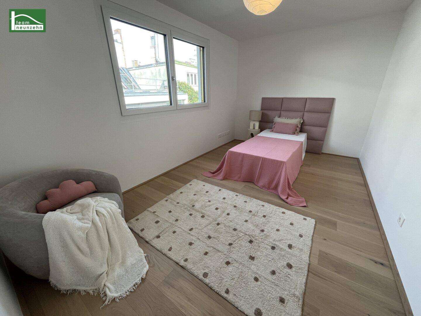 Gemütliches Schlafzimmer mit Einzelbett, Holzboden und einem Fenster, das viel Tageslicht hereinlässt.