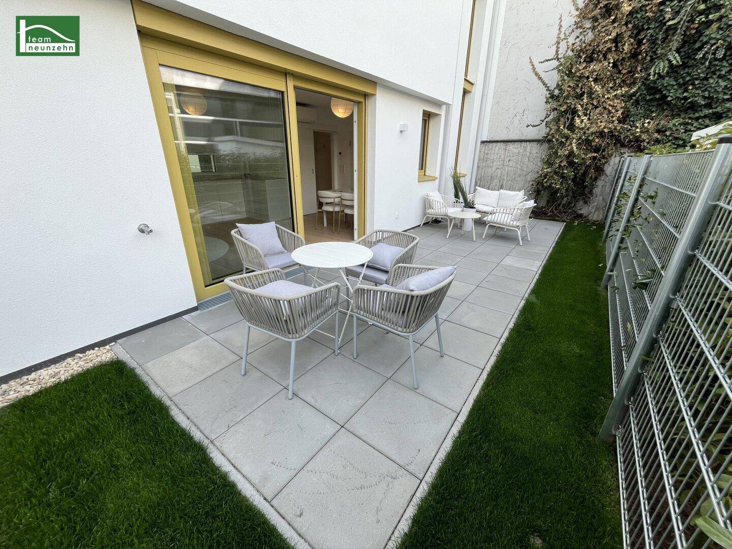 Attraktive Terrasse mit Sitzgelegenheiten und kleinem Rasenbereich, ideal für entspannte Stunden im Freien.