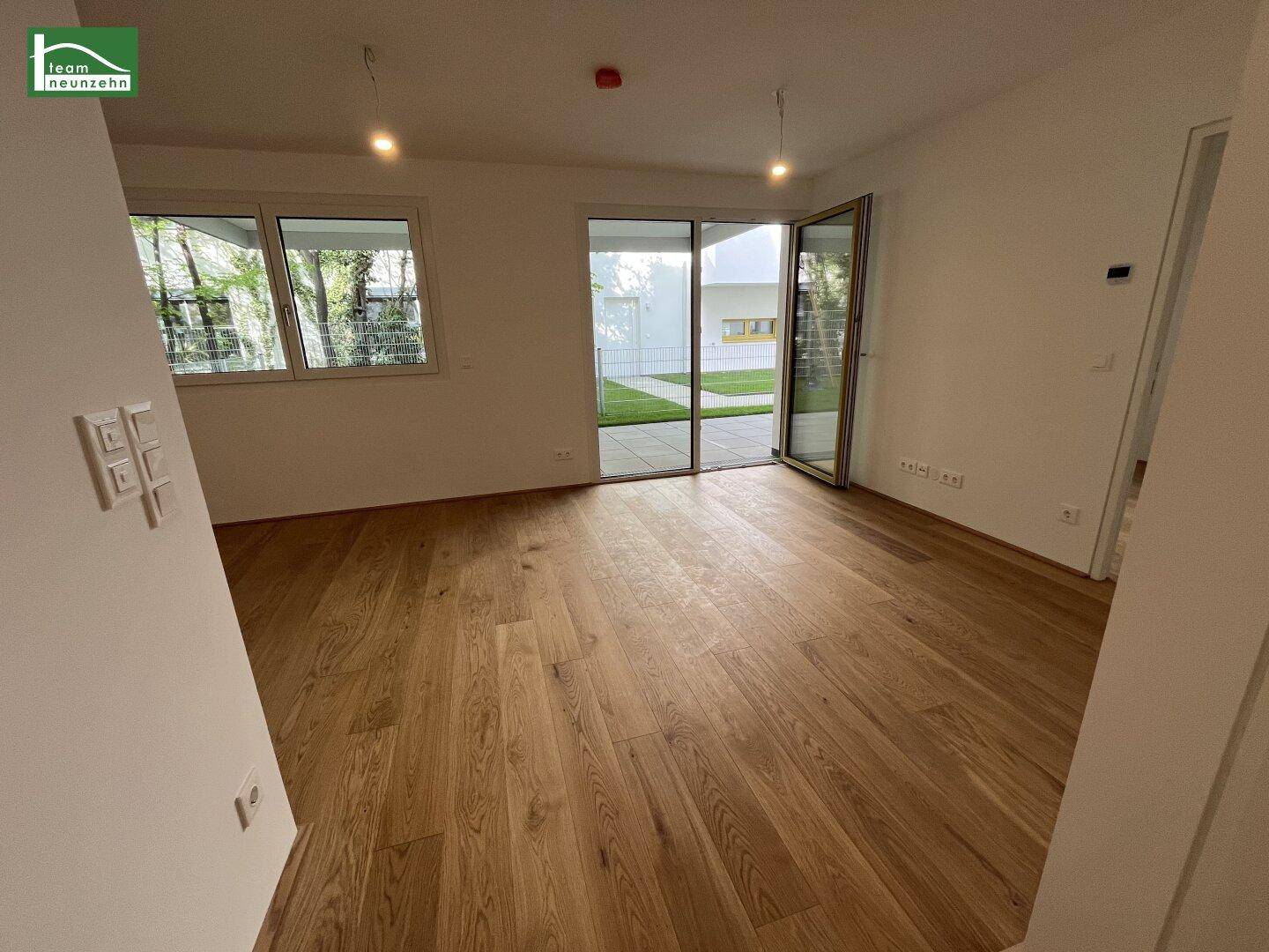 Geräumiges Zimmer mit Eichenparkett und viel Tageslicht durch große Fenster und Terrassentür.